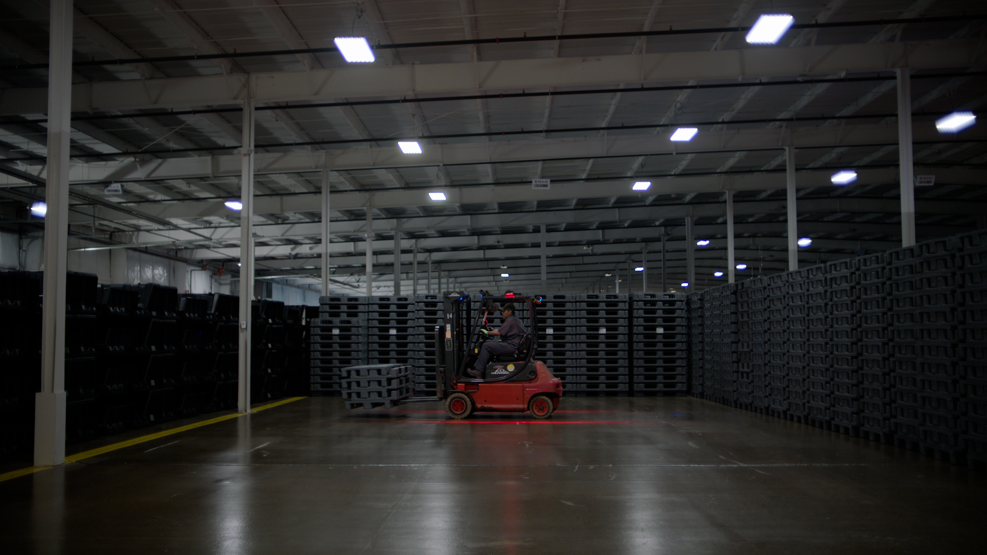 Forklift and stacked reusable pallets in a Shuert warehouse
